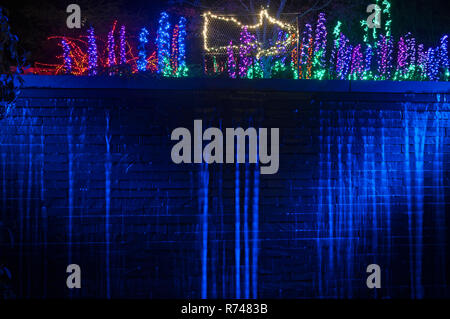 Magnifique chute d'allumé la nuit contre un mur de briques avec des lumières de la nuit au-dessus. La flèche droite en haut du mur. Banque D'Images