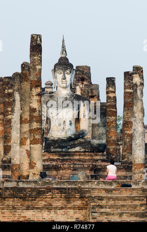 Femme thaïlandaise priant devant un Bouddha assis, Sukhothai, Thaïlande Banque D'Images