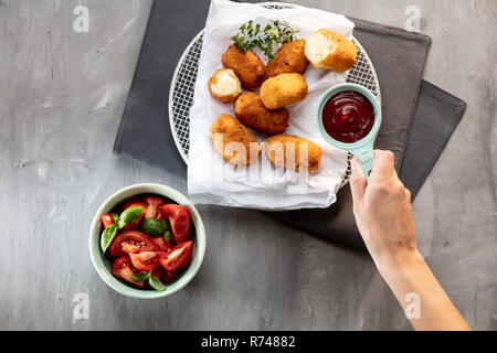 Placer la sauce tomate sur la plaque avec croquettes de pomme de terre, cropped Vue de dessus de la main Banque D'Images