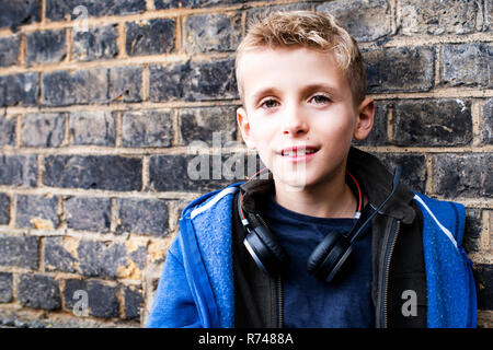 Boy leaning against the brickwall Banque D'Images