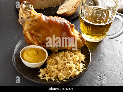 Jarret de porc (eisbein) avec du chou braisé (choucroute) et de la bière sur la table en pierre noire. Banque D'Images