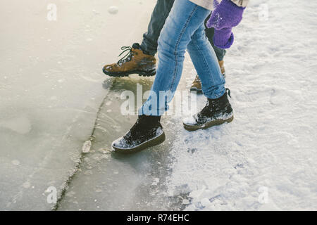 Essayer le danger du pied, contrôle de la mince couche de glace près de la rive. Une paire d'amants à pied par une promenade le long d'un lac gelé d'appuyer sur le pied sur la glace. Banque D'Images
