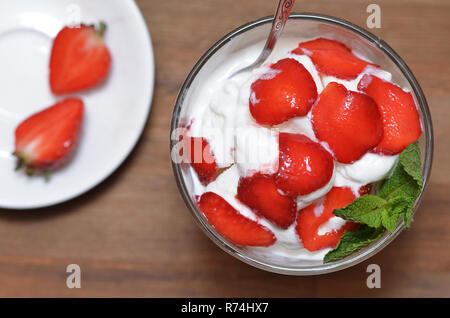 Glace vanille avec les fraises tranchées et de feuilles de menthe dans un bol en verre Banque D'Images