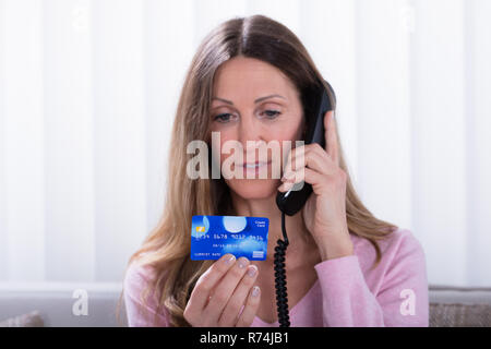 Woman Holding Credit Card While Talking On Telephone Banque D'Images