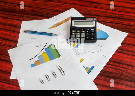 Groupe d'impression de graphiques avec calculatrice, trombones et un stylo sur eux Banque D'Images