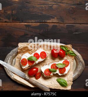 Bruschetta au fromage à la crème, tomates cerises et basilic Banque D'Images