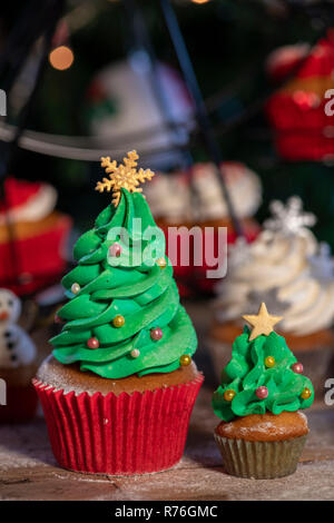 Divers Noël coloré cupcakes avec fond de bois et d'arbres de Noël Banque D'Images