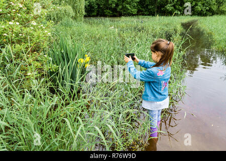 Jeune fille se tient dans l'eau et prend des photos Banque D'Images