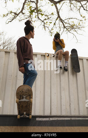 Femme photo tout en cliquant skateur skateur mâle patinage sur la rampe de planche à roulettes Banque D'Images