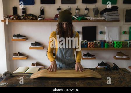 Woman examining skateboard deck en atelier Banque D'Images