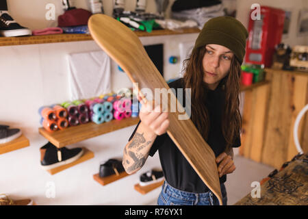 Woman examining skateboard deck en atelier Banque D'Images