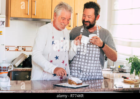 Couple père et fils différents âges et générations à la maison faire un gâteau dans la cuisine ensemble avec bonheur et de s'amuser ensemble Banque D'Images