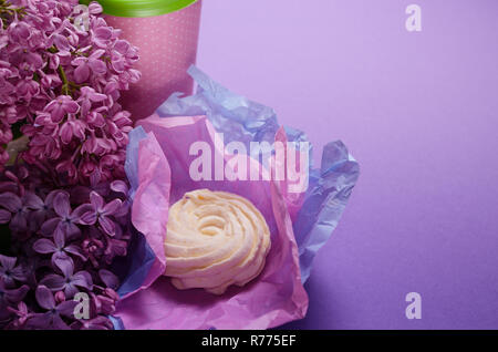 Photo alimentaire composé de Zéphyr, marshmallow en violet, du papier d'emballage et de la coupe du café à emporter. Dessert sucré sur fond rose. Banque D'Images