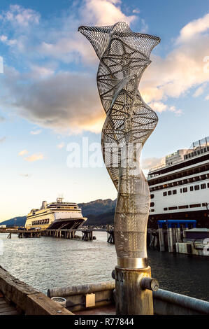 Sculptures abstraites en métal le long du quai du port de navires de croisière, avec des navires amarrés en arrière-plan, en fin d'après-midi au chaud soleil, Juneau, Alaska, USA. Banque D'Images