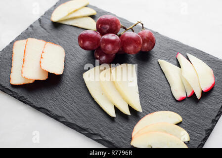 Plateau de fromages mixtes gastronomique starter tapas avec apple et les raisins Banque D'Images