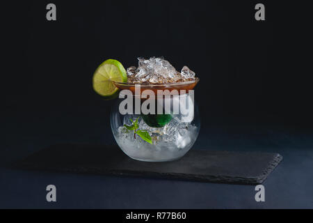 Espresso, Menthe et citron vert cocktail dans un bol en verre moderne. Cold brew café concept. Fond sombre avec copie espace pour un menu. Banque D'Images