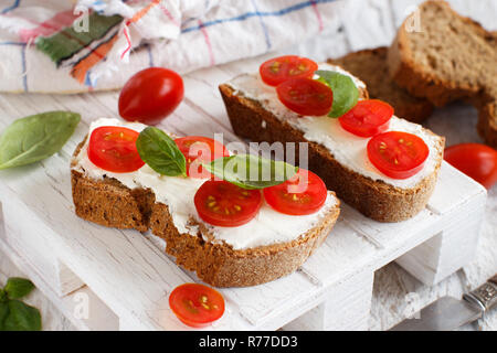 Bruschetta au fromage à la crème, tomates cerises et basilic Banque D'Images