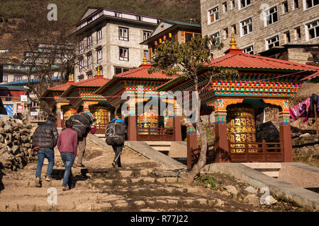 Le Népal, Namche Bazar, porteurs de charges jusqu'étui pour passé fonctionnant à l'eau colorée prière bouddhiste roues auprès d'chemin principal en ville Banque D'Images