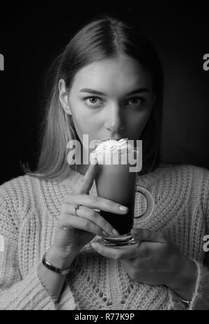 Jolie jeune femme avec un café irlandais. Belle blonde dans un chandail avec une grande tasse de café avec de la crème. Banque D'Images