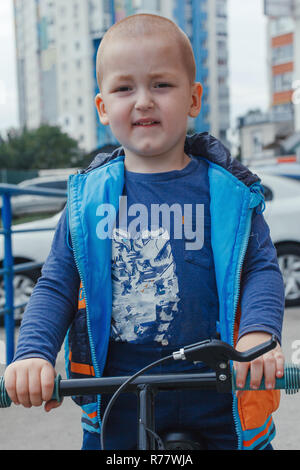 Little Boy riding a suspendre le vélo le long du chemin dans la cour intérieure sur un jour d'été ensoleillé Banque D'Images