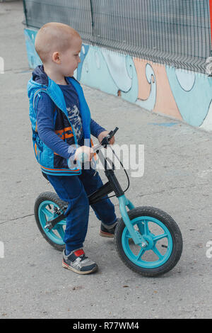 Little Boy riding a suspendre le vélo le long du chemin dans la cour intérieure sur un jour d'été ensoleillé Banque D'Images