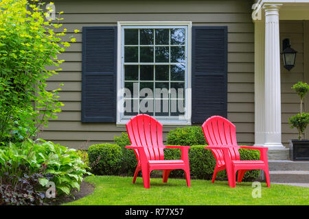 Chaises extérieur rouge sur la pelouse de la cour avant Banque D'Images