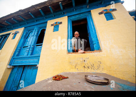 Vieil indien l'homme assis à la porte de sa maison à Sanouli kumaoni, Uttarakhand, Inde village Banque D'Images