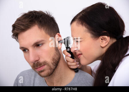 Female Doctor Examining patient de sexe masculin avec l'oreille d'un otoscope Banque D'Images