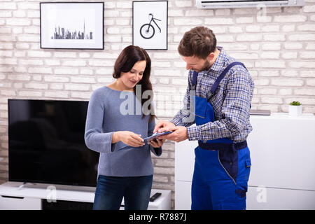 Technicien d'aider les jeunes de sexe masculin dans la Femme à la maison facture Signature Banque D'Images