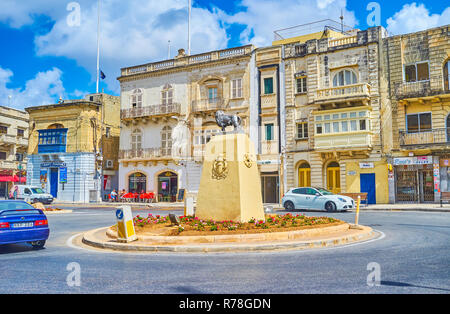 MOSTA, MALTE - Juin 14, 2018 : La statue de lion - le symbole de la ville, au milieu d'U-Turn en rotonde Square occupé avec de vieux édifices sur arrière-plan, sur Banque D'Images