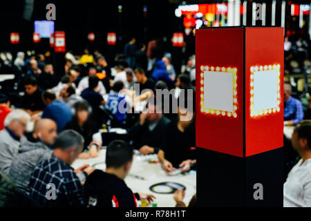 Vue de flou artistique d'un grand tournoi de poker à tables multiples. Les joueurs assis à table et les concessionnaires s'occupant des cartes. Banque D'Images