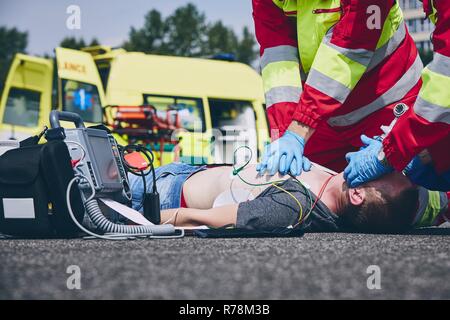 La réanimation. L'équipe de sauvetage (médecin et d'un ambulancier) ressusciter l'homme sur la route. Banque D'Images