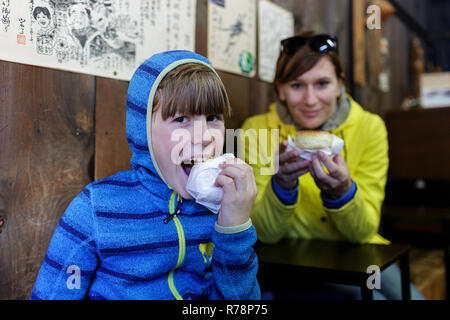 La mère et le fils de manger des boulettes à la vapeur douce japonaise, viande aux, dans une boutique à Tsumago Juku, Honshu, Japan Banque D'Images