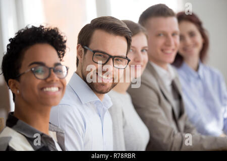 Portrait of smiling employés s'asseoir dans la rangée looking at camera Banque D'Images