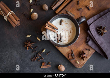 Masala chai indien traditionnel plateau en tasse en céramique avec des ingrédients. Thé noir épicé avec du lait (Masala) sur fond sombre. rustique Banque D'Images