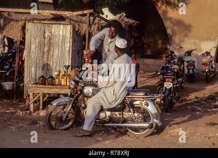 Zinder, Niger. L'essence pour les motos est généralement vendu en bouteilles d'alcool vieux par les vendeurs d'essence côté rue. Banque D'Images