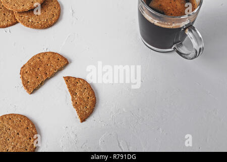 Collation santé concept - avoine à grains entiers de cookies non sucrés et de café noir sur une surface blanche texturée Banque D'Images