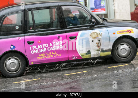 Type Londres taxi noir dans les rues de Blackpool, Royaume-Uni l'exercice de la publicité. Banque D'Images