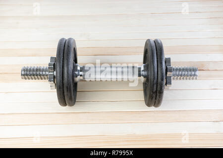 Black metal gym haltère avec chrome poignée d'argent sur fond de bois à haute résolution. concept de perte de forme physique et de poids. Banque D'Images