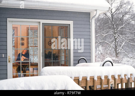 Jeune femme à l'intérieur d'une maison confortable dans une tempête, nord-est des États-Unis Banque D'Images