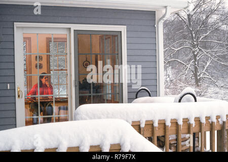 Jeune femme à l'intérieur d'une maison confortable dans une tempête, nord-est des États-Unis Banque D'Images