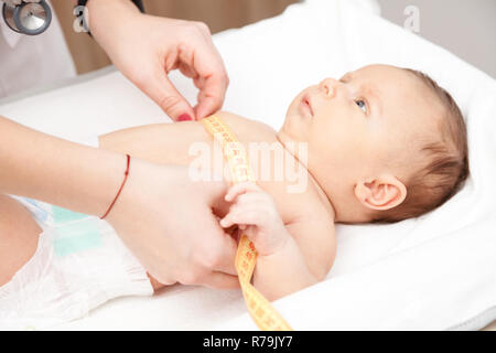 Close-up shot de pédiatre examine deux mois bébé garçon. Médecin à l'aide de ruban de mesure contrôle de taille de la poitrine de bébé Banque D'Images