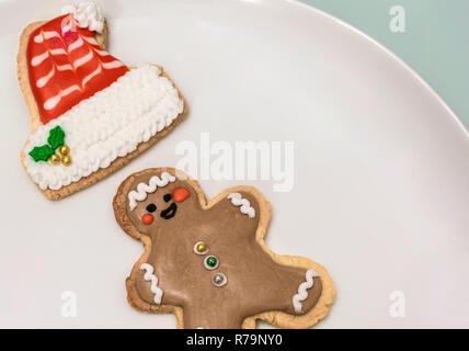 Les cookies de Noël traditionnel avec des formes d'un homme drôle et un chapeau de Père Noël sur une assiette blanche. Des biscuits avec décoration de Noël et de copier l'espace. Banque D'Images