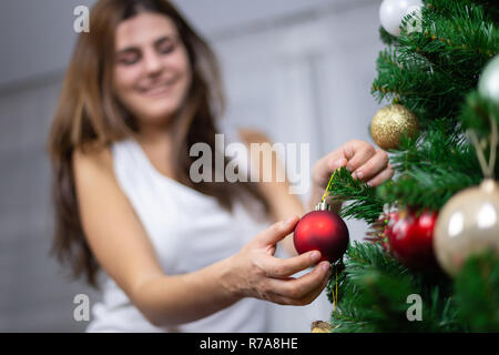 Belle jeune femme souriante et pendaison petit hochet on Christmas Tree Banque D'Images