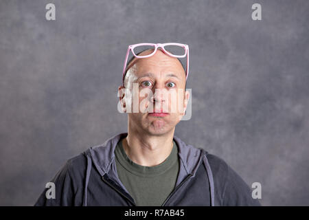 Homme à lunettes roses à étonné à la caméra Banque D'Images