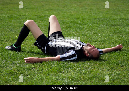Joueur de football en étant couché sur l'herbe Banque D'Images