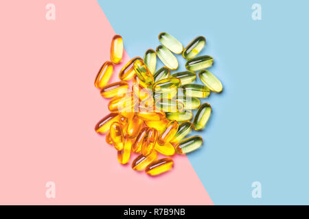 Une pile d'un jaune vif des capsules d'huile de poisson sur fond bleu et rose vif tourné avec studio light Banque D'Images
