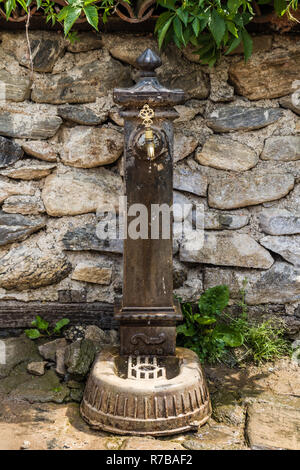 Brass Metal Fontaine sur une ancienne colonne de marbre devant un mur de pierre Banque D'Images