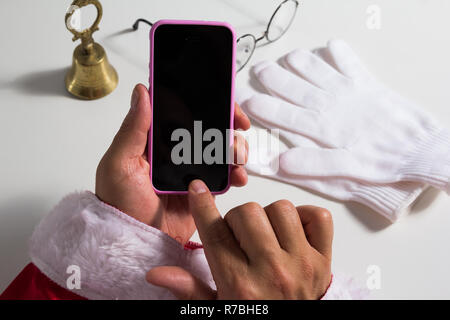 Point de vue de Santa Claus (ou Saint Nicolas) mains touchant l'écran de téléphone cellulaire. Banque D'Images