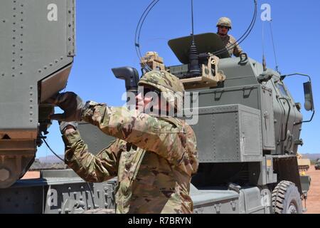 Le s.. Hendrik Rijfkogel, bas, renvoie l'équipement pour un lance-roquettes, tout en pratiquant le chargement et déchargement rocket pods à Orogrande, N.M., 4 mai 2017. La CPS. Dustin Feldman, haut, les regarde. Les soldats sont affectés à une batterie, 2e bataillon du 130e Régiment d'artillerie de la Garde nationale du Kansas. Banque D'Images